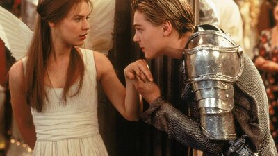 Romeo + Juliet Woman stands with wings, man holds her hand to kiss it