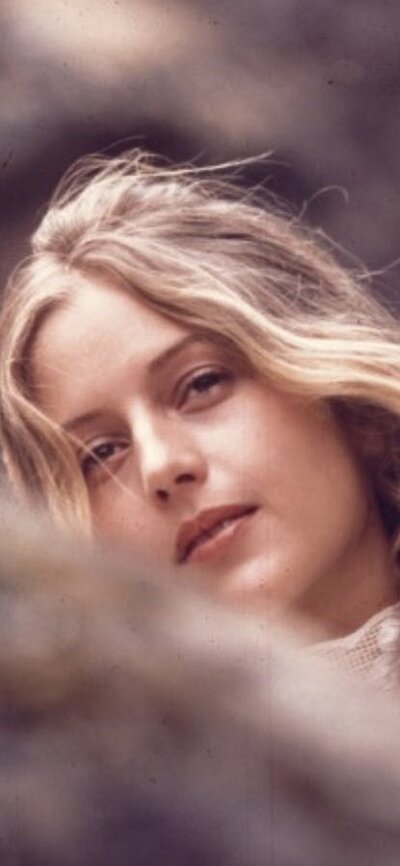 Picnic at Hanging Rock Woman looking at camera, slightly hidden behind tree