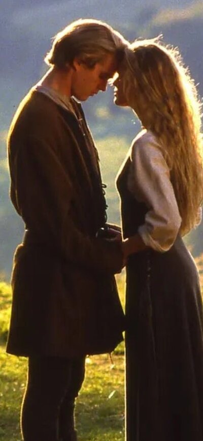 A woman and man embrace with a field in the background