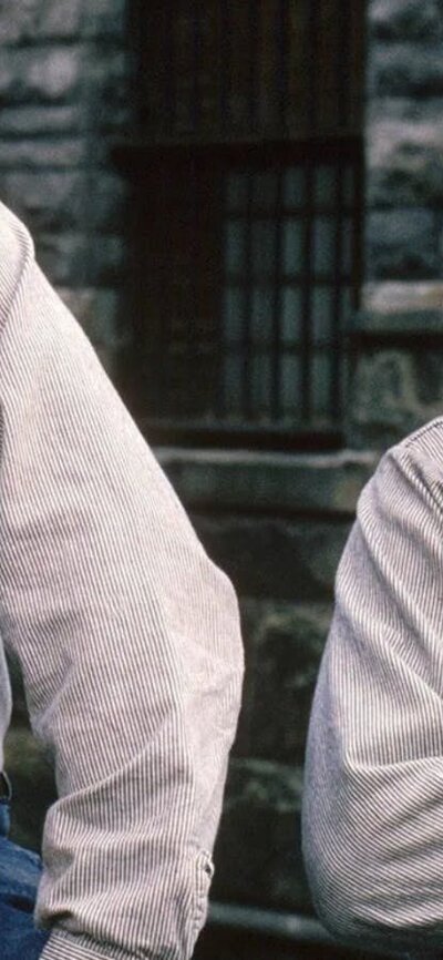 Two men dressed in prison shirts