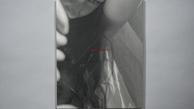An image of a book on a grey background. On the cover is a photograph of a girl with long hair.