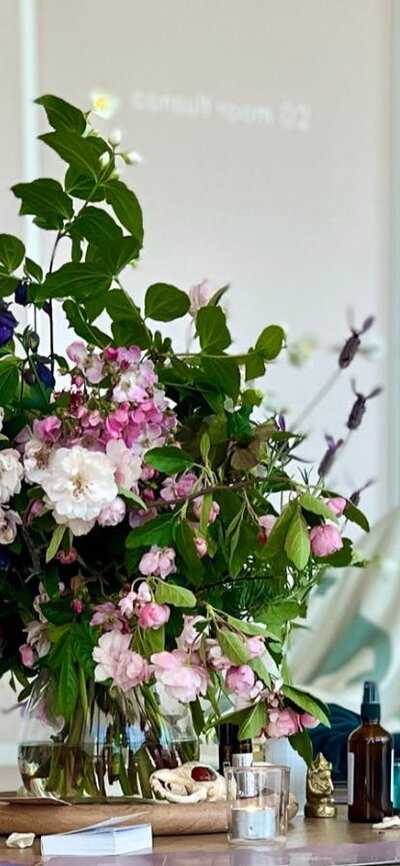 Seasonal flowers in the foreground with participants resting on mats during breathwork mastery