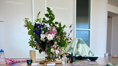 Seasonal flowers in the foreground with participants resting on mats during breathwork mastery
