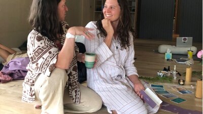 Two women sitting together talking and smiling during a breathwork mastery retreat