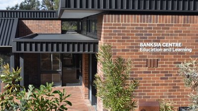Banksia centre education and learning sign on building with banksia flower in foreground