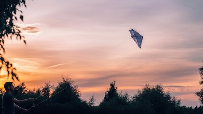 Man flying kite at sunset in scenic landscape