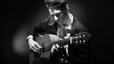 Black and white photo of Callum Henshaw holding a guitar