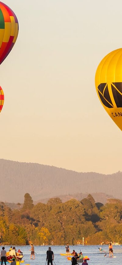 Four floating hot air balloons over lake in Canberra