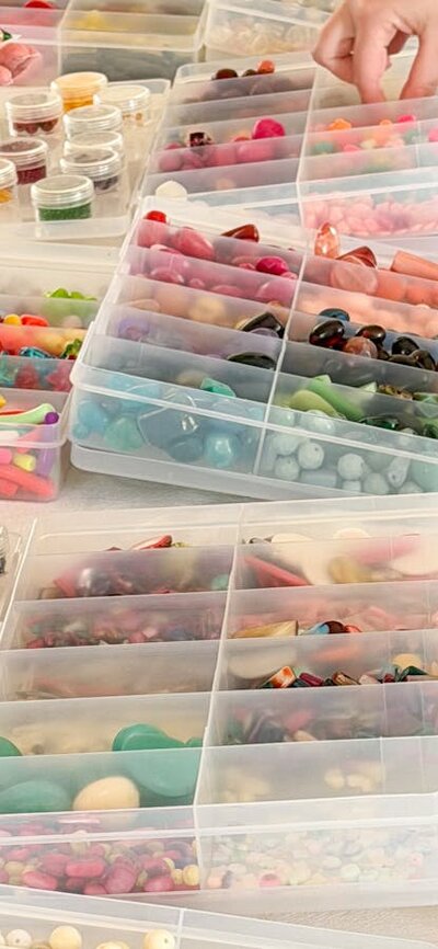 Table covered in plastic containers that hold an array of colourful beads