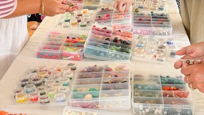 Table covered in plastic containers that hold an array of colourful beads