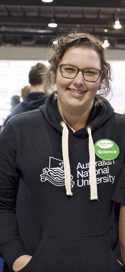 Three staff at the ANU booth smiling.