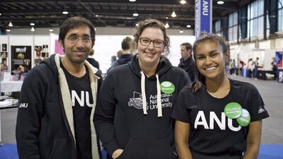 Three staff at the ANU booth smiling.