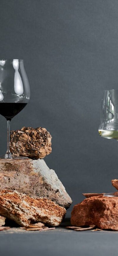 Learn about the soils of the wine region at the Canberra Cellar Door Glasses of wine are balanced on top of red clay soils in a studio shot.