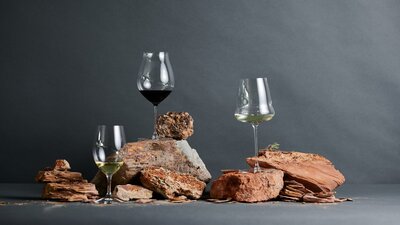 Learn about the soils of the wine region at the Canberra Cellar Door Glasses of wine are balanced on top of red clay soils in a studio shot.