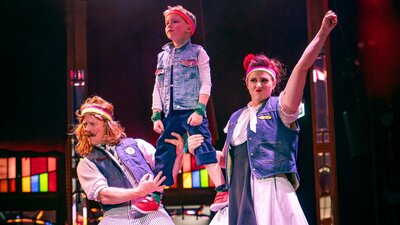 A family dressed as 80's rockstars perform a human pyramid.