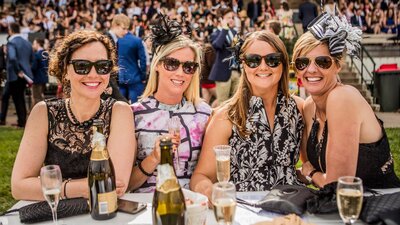 Fashion and champagne Four ladies dressed for the races enjoying champagne