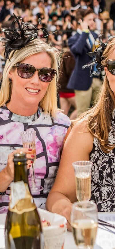 Four ladies dressed for the races enjoying champagne