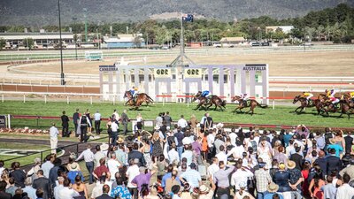 View of horses crossing the finishing post in front of a crowded stand