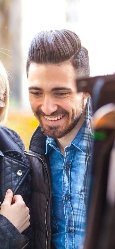 lady and a man smiling at clothing hanging up at an outdoor market