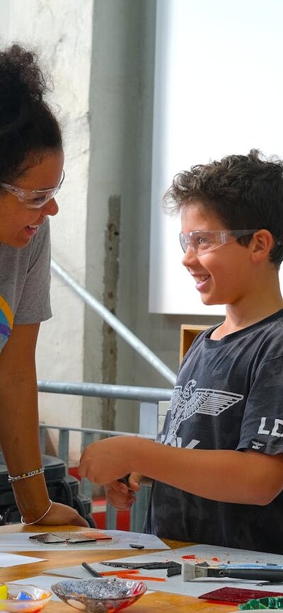 Kilnforming school holiday programs at Canberra Glassworks Participants smiling and cutting glass in Glassworks Engine Room
