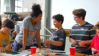 Kilnforming school holiday programs at Canberra Glassworks Participants smiling and cutting glass in Glassworks Engine Room