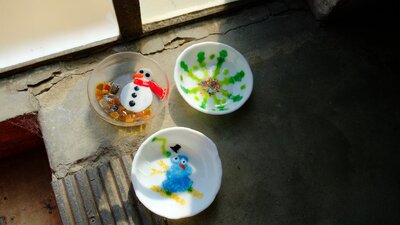 3 glass bowls made through kiln forming, two with snowman deisgns, and one with a colourfull snowfla