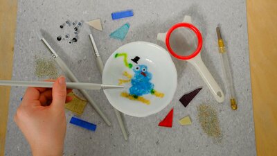 Painting with Frit Bowl Hand moving glass frit around a design for a kilnformed bowl. With all the tools surrounding
