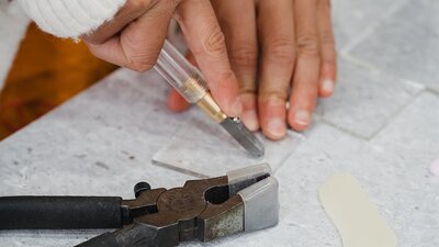 Childs hand cutting a piece of glass with special tools and matt