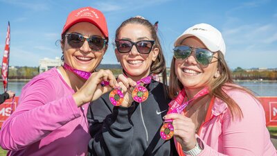 3 women celebrating with their finisher medals.