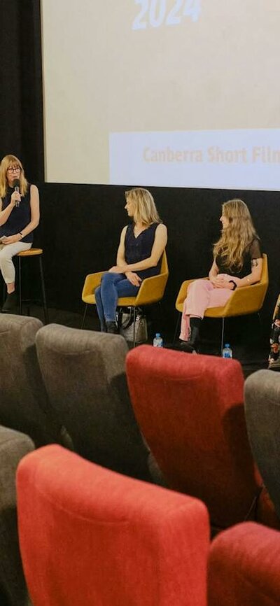 Panel at a previous CSFF screening The image depicts a panel discussion taking place in front of a cinema screen