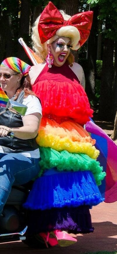 motorbike ridden by woman and drag queen passenger