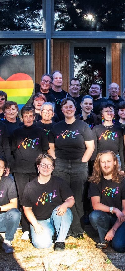 Picture of Canberra QWIRE people smiling and holding rainbow heart banners