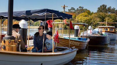 A variety of traditional boats line the dock Several boats at BoatFest 2024
