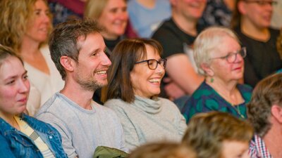 An audience sitting in a crowd with smiling faces.