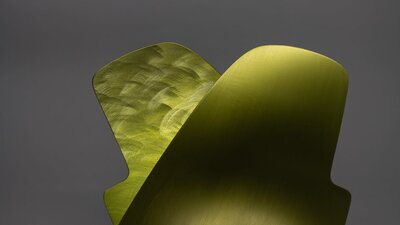 A lamp made from a thin sheet of folded burnished metal in an abstract shape.