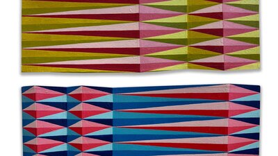 Rectangles of card, with undulating folds, and painted patterns of elongated lozenges, from above.