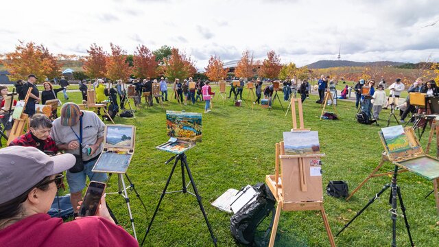An artist's easel with a fresh artwork an artists easel with an artwork in front of a view of canberra and lake burley griffin