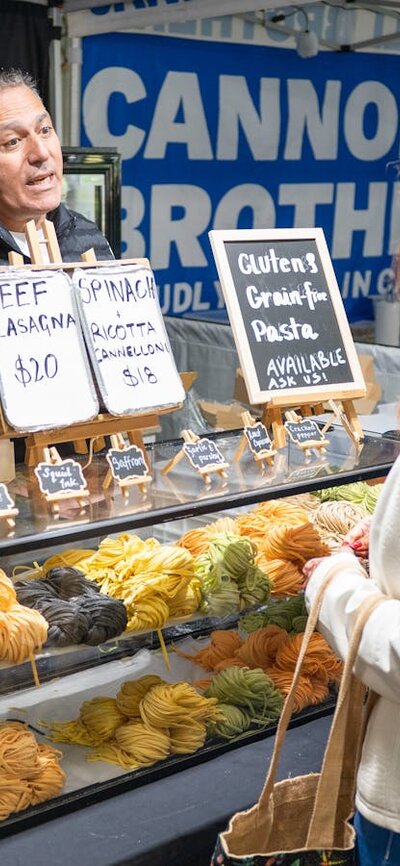 shoppers selecting fresh pasta from local farmers market in Canberra