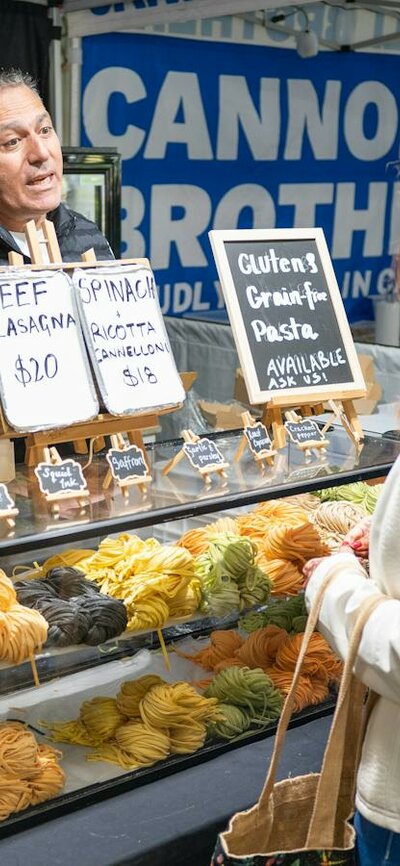 shoppers selecting fresh pasta from local farmers market in Canberra
