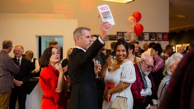 CAPO Art Auction 2019 Guests holding their arms up with bidding sheets during a live auction