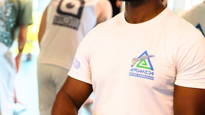 A man stands smiling while playing an atabaque