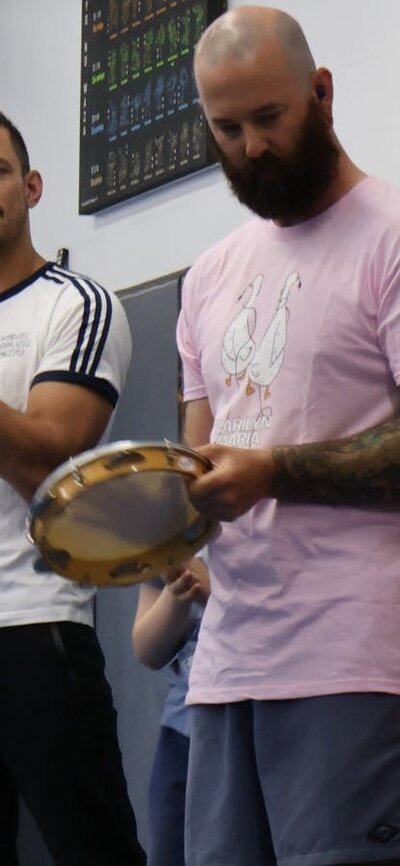 A group of adults and kids stand together playing music and clapping