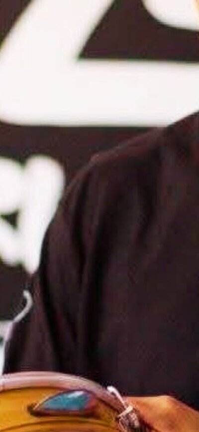 A man in a black long sleeve shirt plays a pandeiro