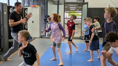 A man teaches a group of children Capoeira movements