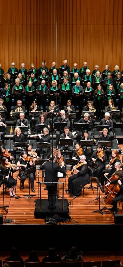The Armed Man concert 5 July 2025 Large orchestra, piano and choir on stage with Louis Sharpe conducting.