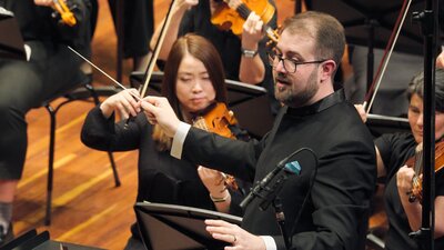 Louis Sharpe conducting, July 2024 Louis Sharpe conducting performance with female violin players in the background