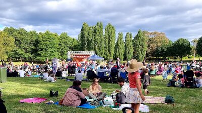 people sitting on a grass field watching Carols in Town Park Canberra