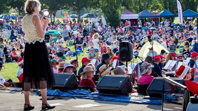 performer on stage with audience inb background at Carols in Town Park Canberra