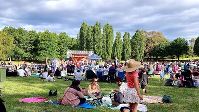 people sitting on a grass field watching Carols in Town Park Canberra