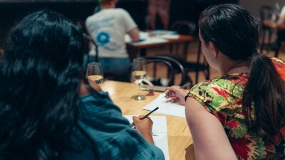 People facing away from the camera with pencils and paper
